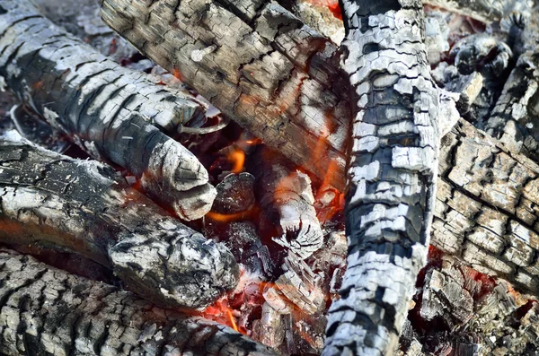 Madera carbonizada ardiendo en el resplandor del fuego, primer plano — Foto de Stock