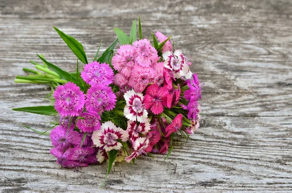 Bouquet of small carnations on a wooden background — Stock Photo, Image