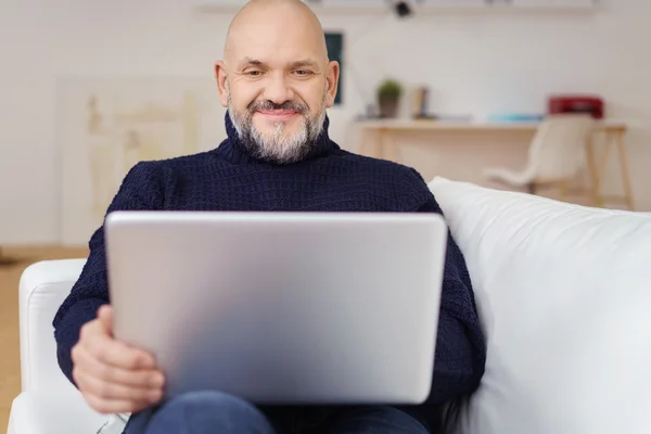 Nöjd mogen Man använder Laptop hemma på soffan — Stockfoto