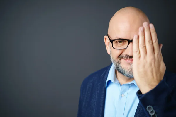 Homme avec barbe et lunettes couvrant le visage avec la main — Photo