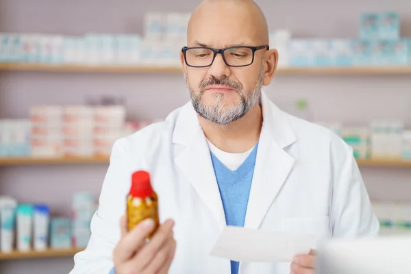 Farmacêutico verificando comprimidos contra receita médica — Fotografia de Stock