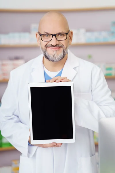 Smiling pharmacist displaying a blank tablet — Stockfoto