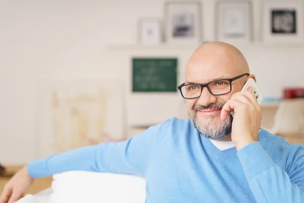 Usmívající se dospělý muž mluvící v mobilním telefonu domů — Stock fotografie