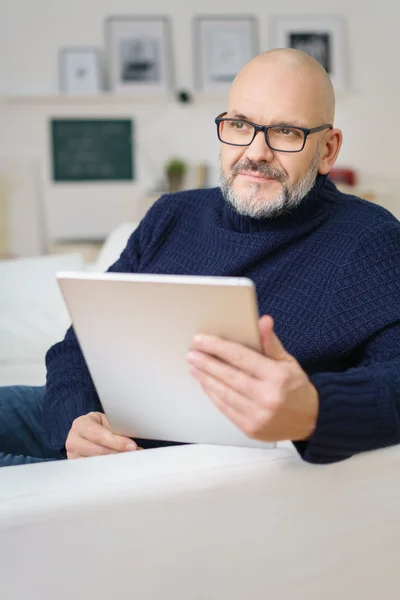 Задумчивый мужчина средних лет держит планшет — стоковое фото
