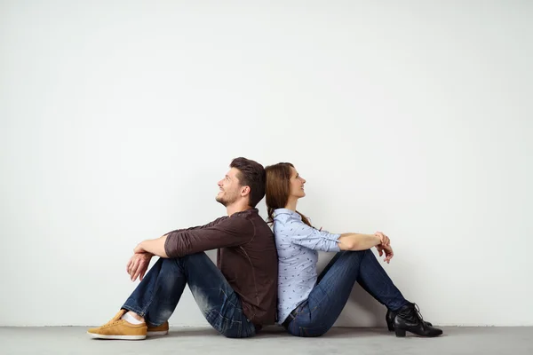 Young couple sitting back to back — Stock Photo, Image