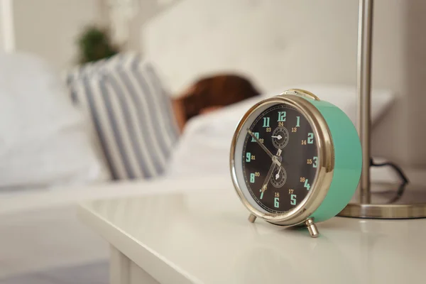 Alarm clock about to ring alongside a sleeper — Stock Photo, Image