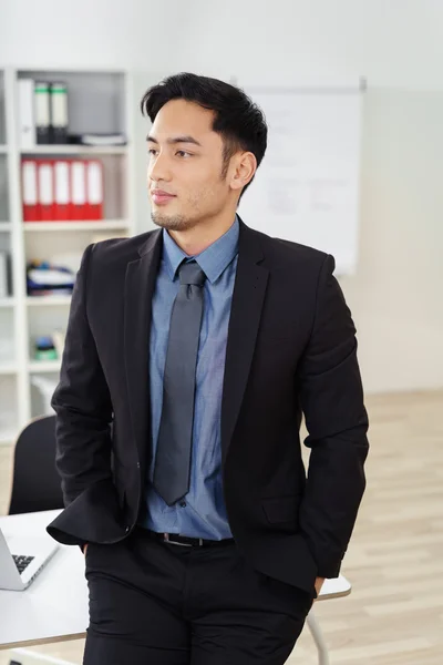 Selbstbewusster junger Geschäftsmann stützt sich auf den Tisch — Stockfoto