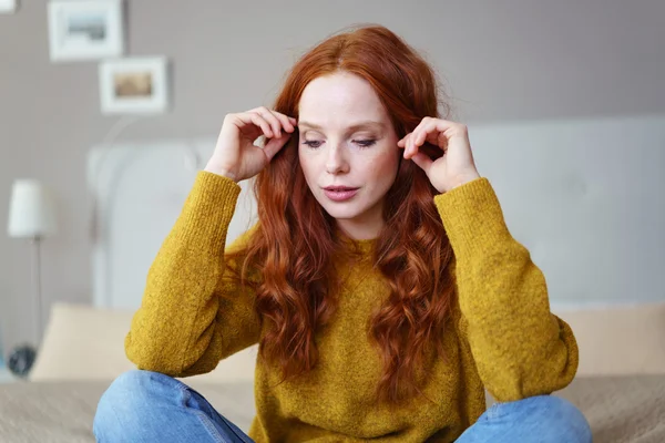 Serious woman sitting and adjusting hair — Stock Photo, Image