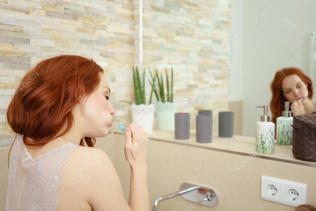 Young Redhead Woman Brushing Teeth in Bathroom — Stock Photo © racorn