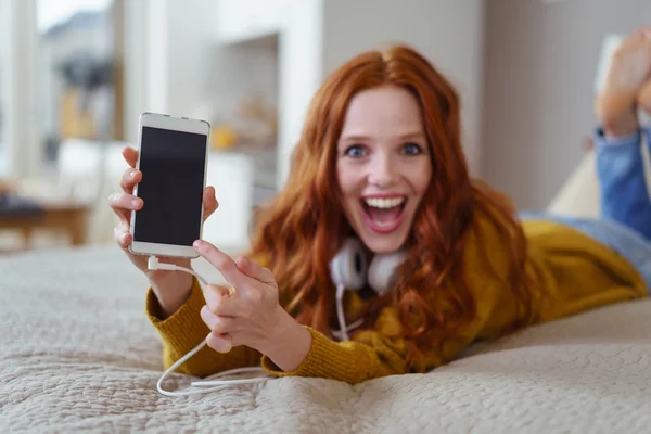 Jeune femme excitée pointant vers son mobile — Photo