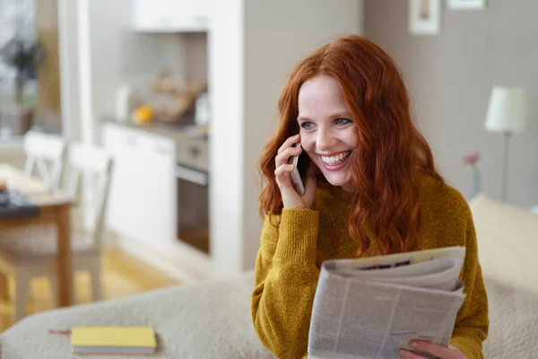 Woman relaxing with a newspaper and mobile phone — Stockfoto