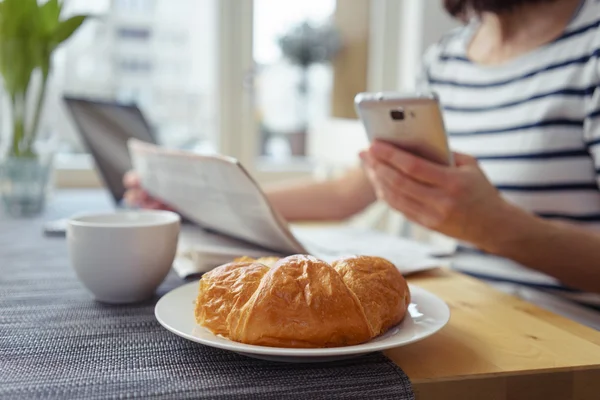 Donna con cellulare che fa colazione Croissant — Foto Stock