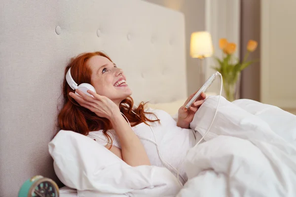 Jeune rousse femme se détendre avec de la musique au lit — Photo