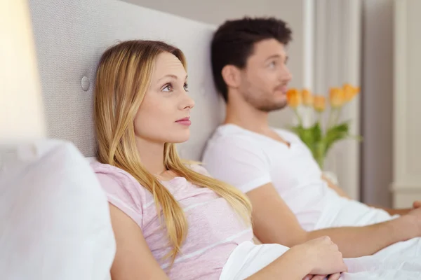 Pareja joven sentada en la cama viendo la televisión — Foto de Stock