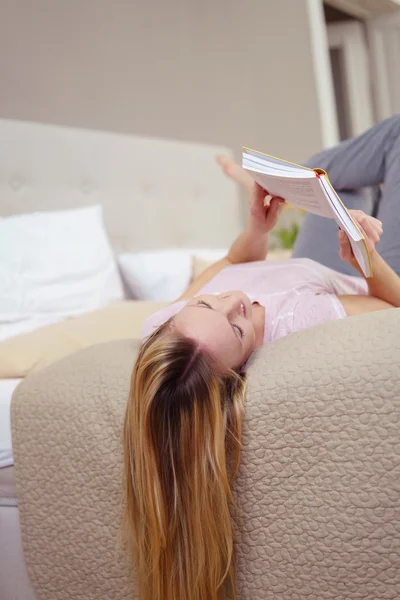 Jovem relaxante lendo um livro em uma cama — Fotografia de Stock