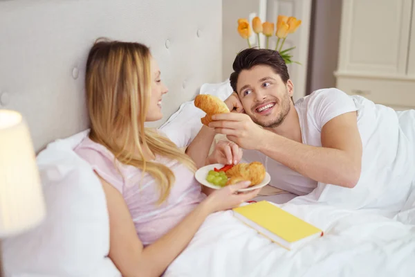 Romántica pareja joven compartiendo el desayuno en la cama —  Fotos de Stock