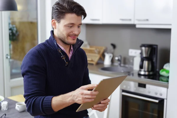 Handsome young man using a tablet at home — Stock Photo, Image