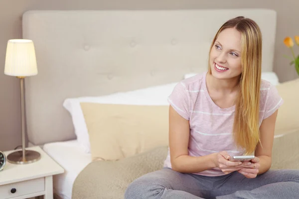 Attractive blond woman sitting on her bed — Stock Photo, Image