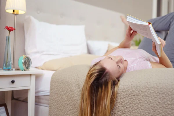 Mujer joven relajada acostada en una cama leyendo — Foto de Stock