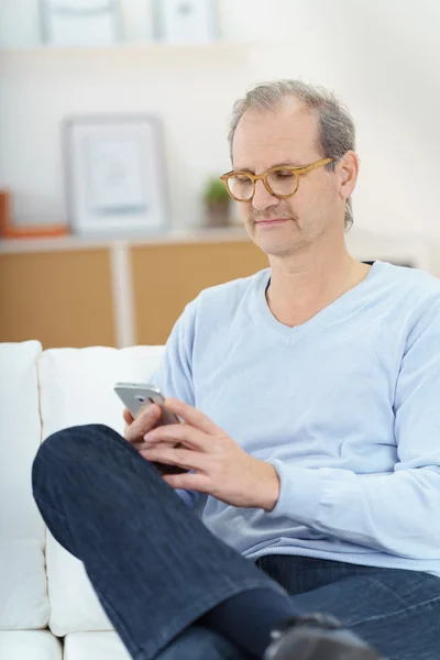 Spokojny człowiek z skrzyżowanymi nogami sprawdzanie telefonu — Zdjęcie stockowe