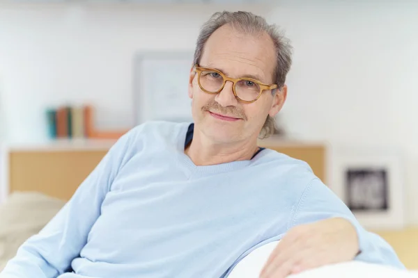 Jistý střední letitý muž sedí v pohovce — Stock fotografie