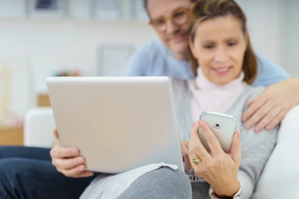 Paret tittar på laptop och telefon på soffa — Stockfoto