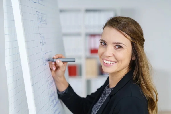 Lachende vrouw schrijven op grote grafiek — Stockfoto