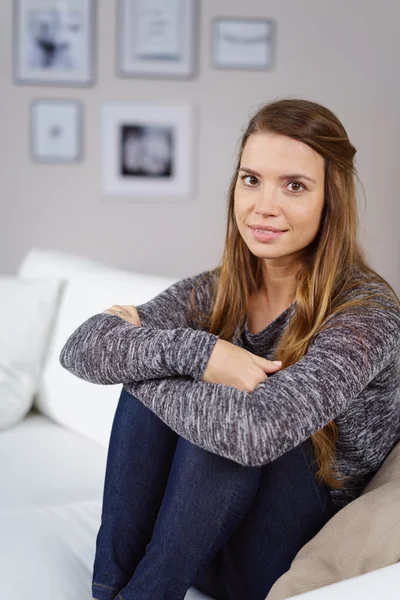 Grinsende Frau sitzt auf Sofa — Stockfoto