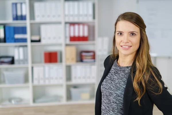 Grinning woman standing in small office — Stock Photo, Image