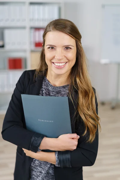 Fröhlicher Arbeiter hält Ordner in kleinem Büro — Stockfoto