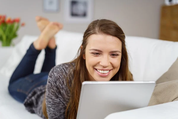 Glückliche junge Frau liest auf ihrem Tablet-PC — Stockfoto