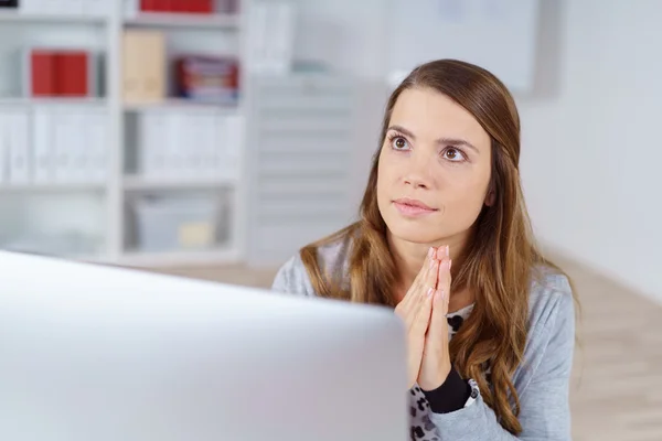 Young woman with palms together at computer — Stok fotoğraf