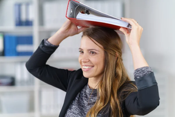 Fröhliche junge Büroangestellte balanciert einen Ordner — Stockfoto