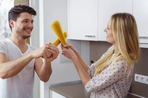 Homme et femme jouent à se battre avec des pâtes — Photo