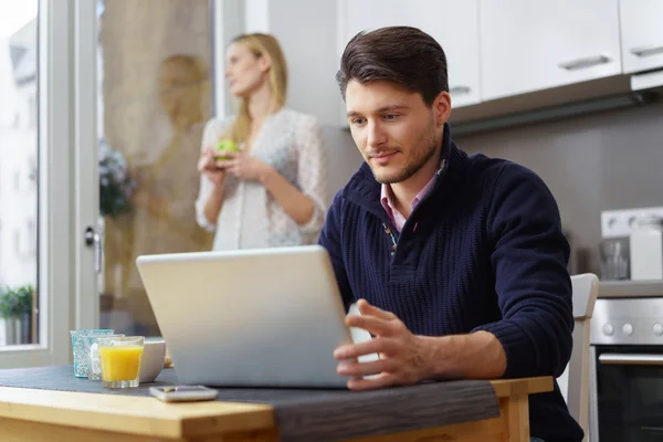 Jonge man aan het werk op zijn laptop in de keuken — Stockfoto