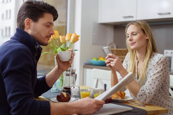 Young couple distracted with reading at table — Stockfoto