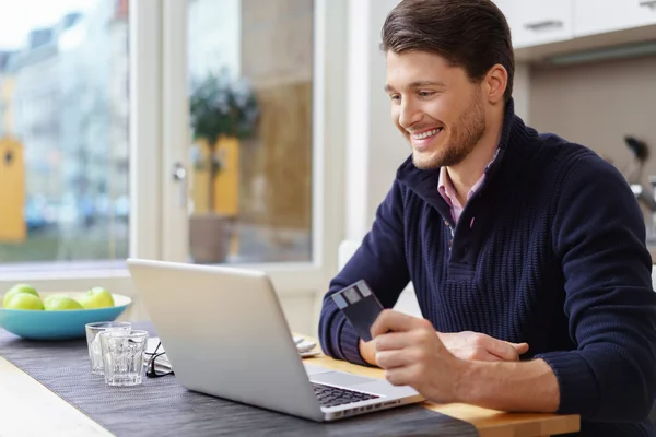 Homem sorridente com cartão de crédito e laptop — Fotografia de Stock