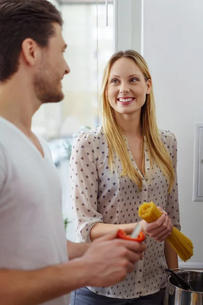 Young woman holding pasta with man in kitchen — 图库照片