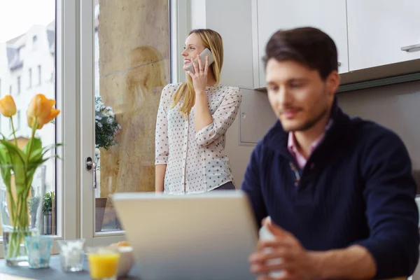 Woman standing near a window on a phone call — Stock fotografie