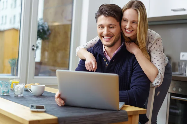 Donna ridente appoggiata sull'uomo felice usando il computer portatile — Foto Stock