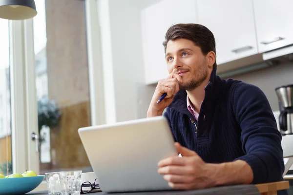 Grinning barbudo homem com laptop na cozinha — Fotografia de Stock