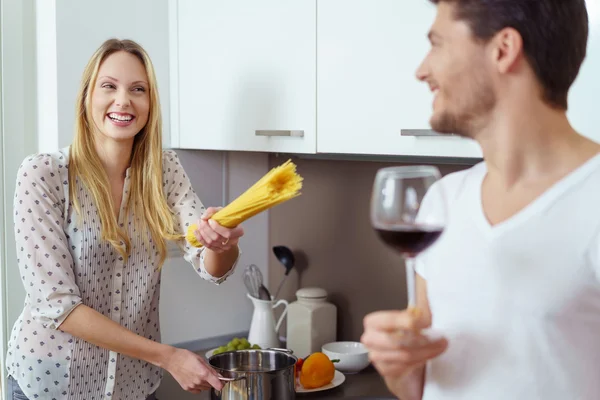 Lachende blonde Frau zeigt mit Nudeln auf Mann — Stockfoto