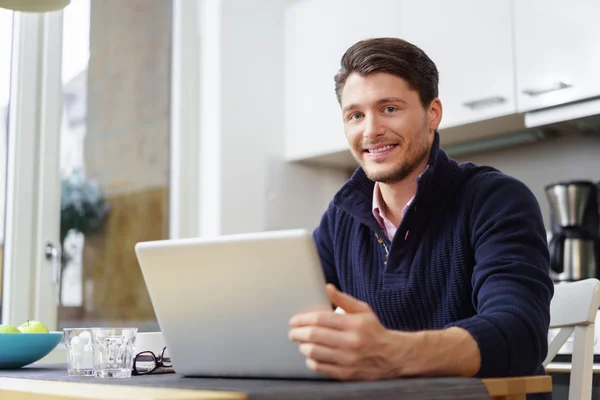 Schöner bärtiger Mann mit Laptop auf dem Tisch — Stockfoto