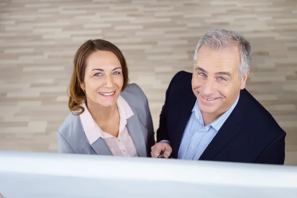 Dos ejecutivos sonrientes mirando hacia arriba desde el gráfico —  Fotos de Stock