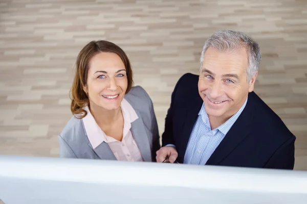 Zwei lächelnde Führungskräfte, die vom Chart nach oben blicken — Stockfoto