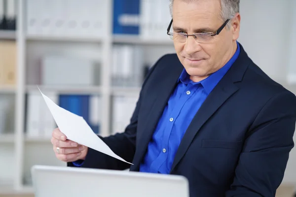 Empresário verificando um documento em um laptop — Fotografia de Stock