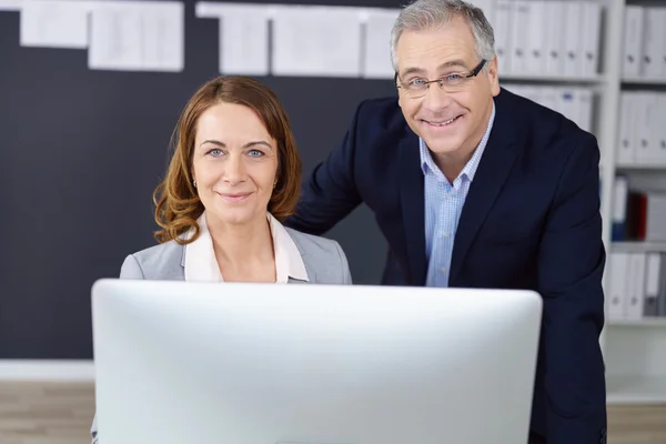 Reife Führungskräfte grinsen am Computer — Stockfoto