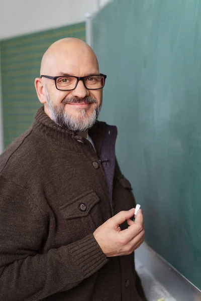 Bearded teacher about to write on chalkboard — Stock Photo, Image