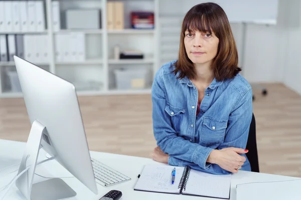 Ernste Frau mit verschränkten Armen auf dem Schreibtisch — Stockfoto