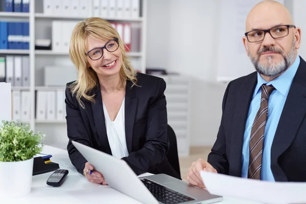 Laughing business woman next to serious co-worker